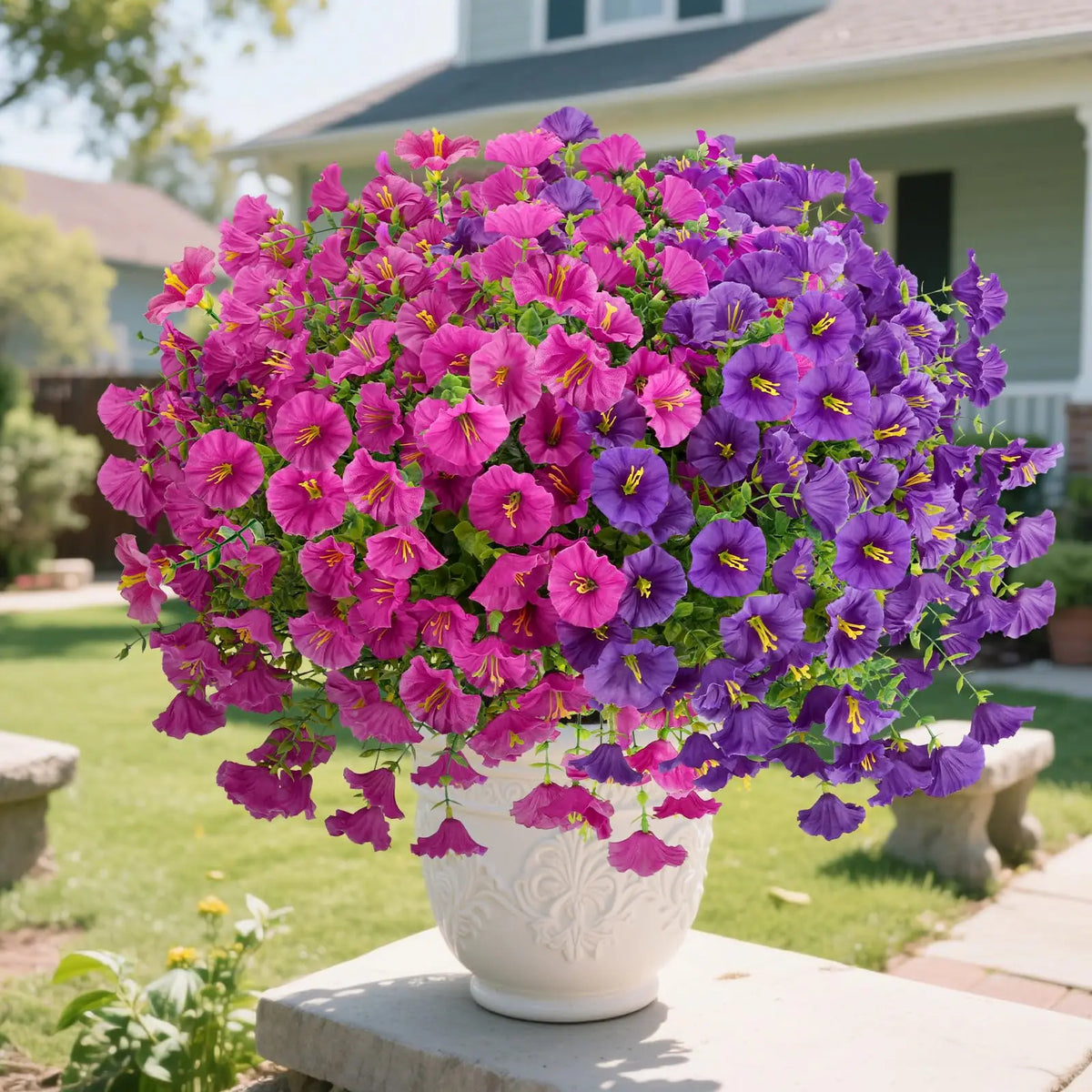 A large bouquet of vibrant purple and pink artificial silk flowers in a white vase set outdoors.