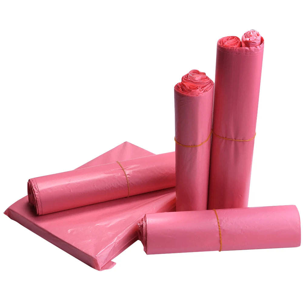 A stack of pink plastic self-adhesive shipping pouches in various rolls and flat sheets.
