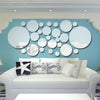 A light blue wall decorated with a cluster of round mirrors and a white sofa.
