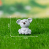 A small white animal figurine resembling a sloth is placed on green grass.