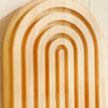 A close-up of geometric wooden wall shelves with parallel grooves and rounded arches.