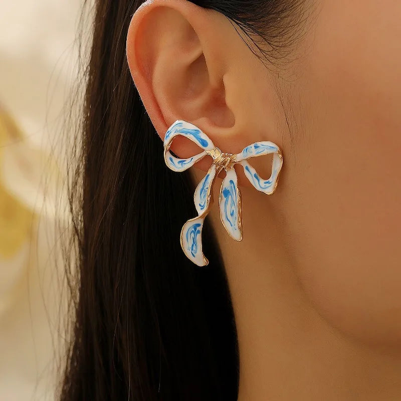 Gold-toned bow stud earrings featuring blue and white porcelain design