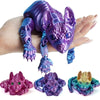 A hand holds a purple articulated sphynx cat figurine, with several smaller versions displayed below.