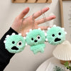 A hand holds three bright green plush keychain charms with white accents and clear photo card holders.