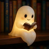 A cute ghost night light shaped like a translucent figure is illuminating an open book.