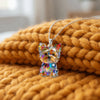 A colorful acrylic pendant necklace shaped like a Yorkshire Terrier is displayed on a knitted orange blanket.