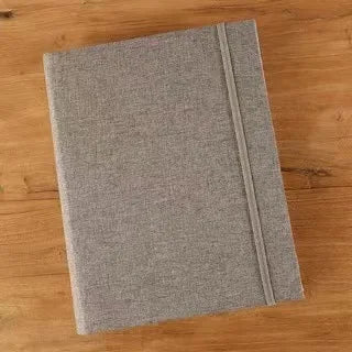 A gray linen photo album with a textured cover lying on a wooden surface.
