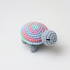 Handmade crocheted turtle plush with a colorful, striped shell and gray body.