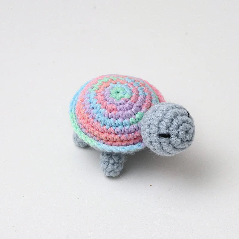 Handmade crocheted turtle plush with a colorful, striped shell and gray body.