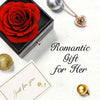 Un coffret cadeau avec une rose rouge conservée, un collier en or et une sphère dorée sur fond blanc.