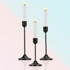 A set of three modern black metal taper candle holders with white pillar candles.