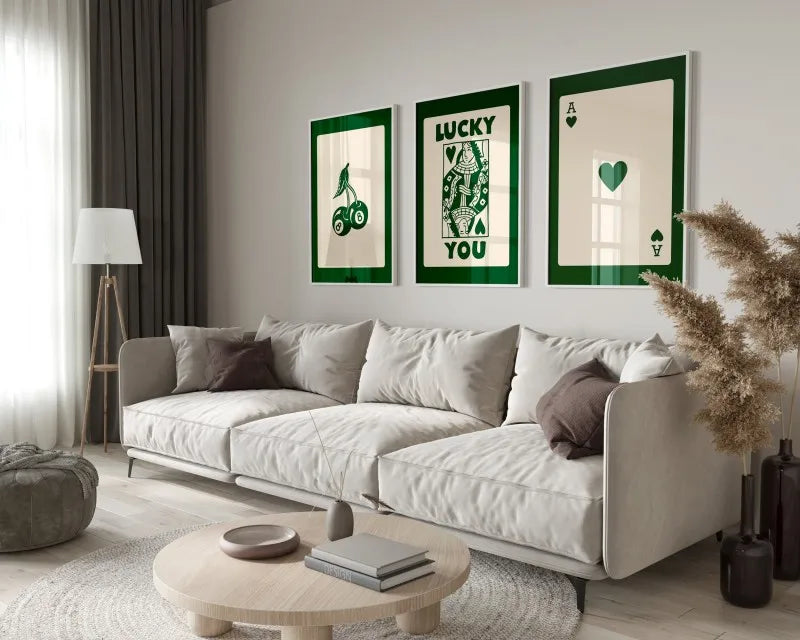 A modern living room features a light sofa, green accent walls, and framed art prints on the wall.