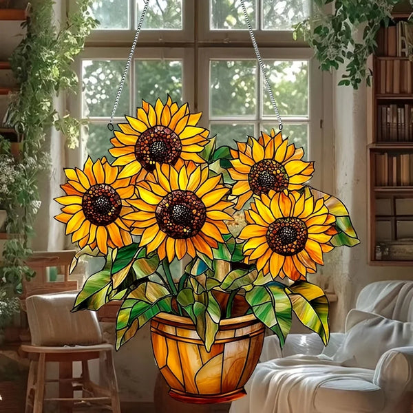 A vibrant bouquet of yellow sunflowers in an orange pot hangs in front of a window.