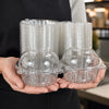 Clear glass cupcake boxes stacked and held by a person