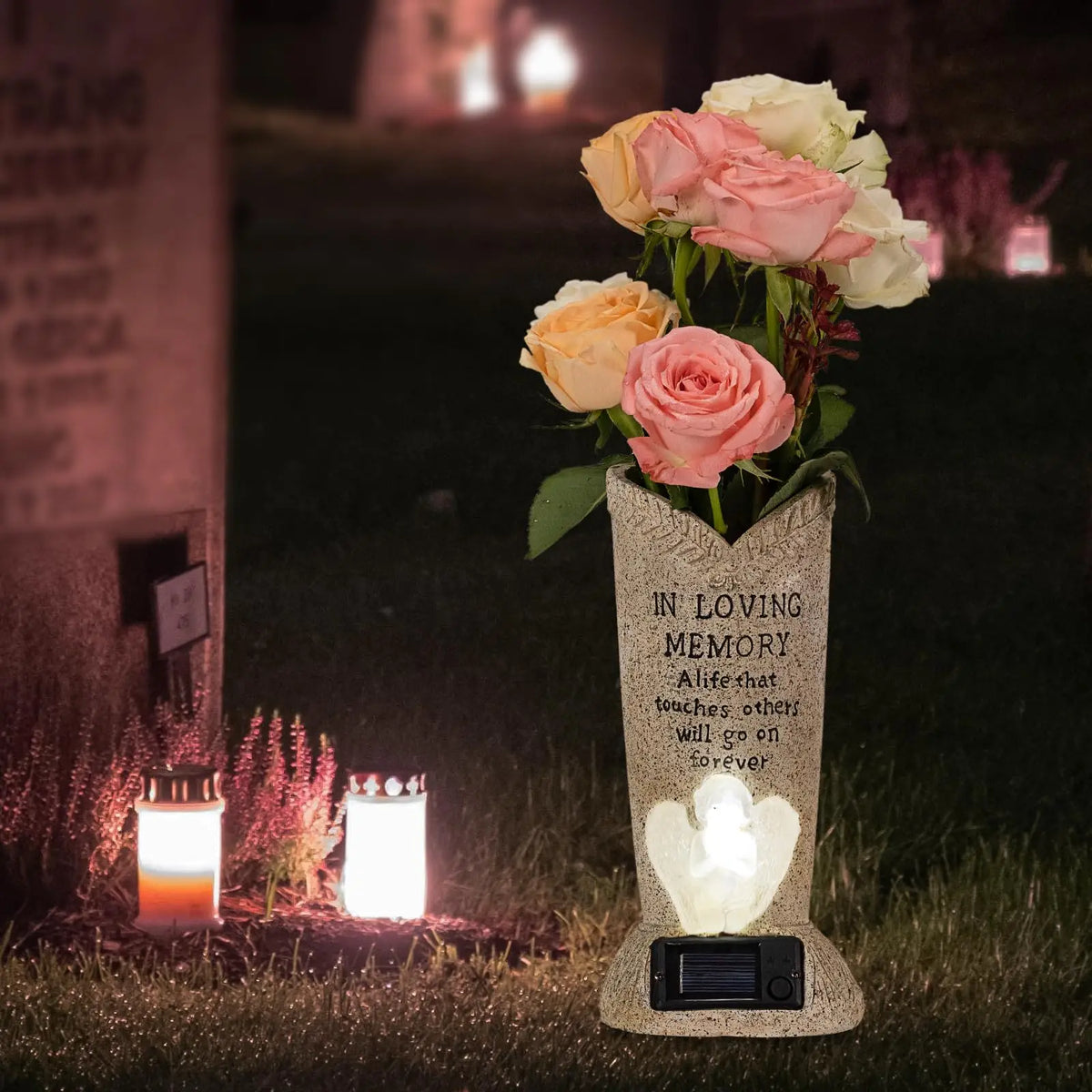 A floral arrangement of pink and white roses in a concrete vase set into the ground with an embedded solar light and speaker.