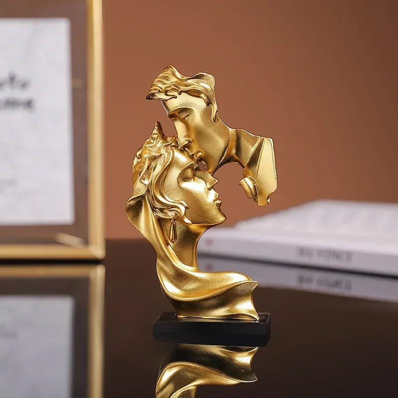 Statue en résine dorée de deux profils s'étreignant, reflétant la lumière sur une surface sombre.