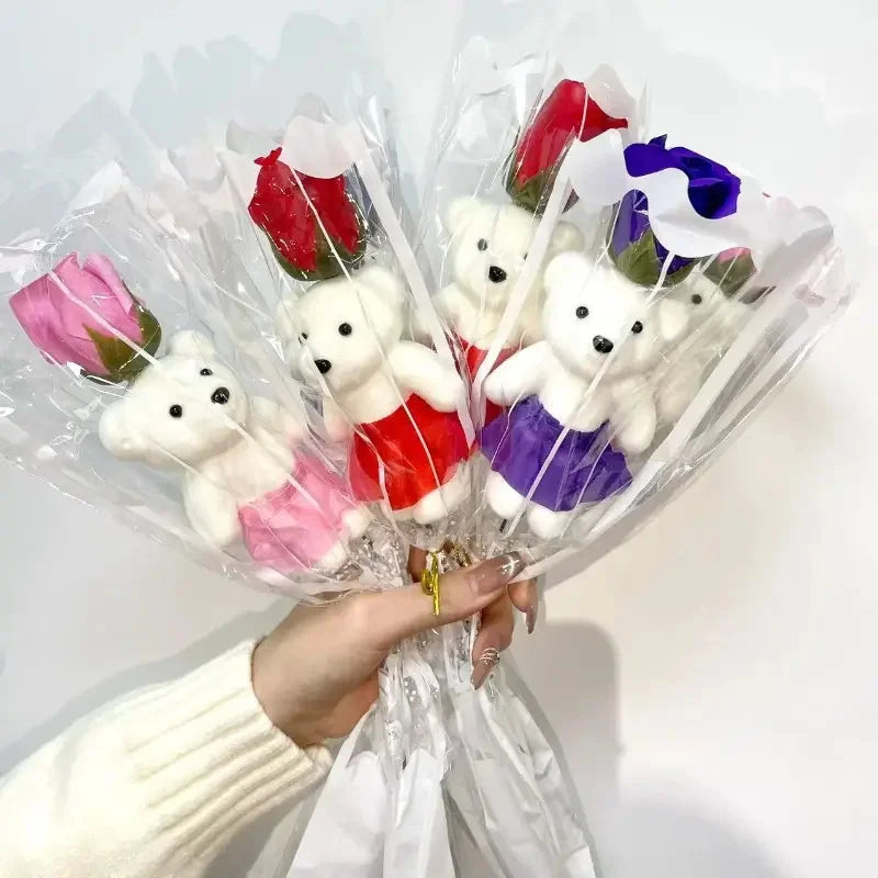 A bouquet of artificial rose soap featuring white teddy bears with red and purple accents, wrapped in clear plastic.