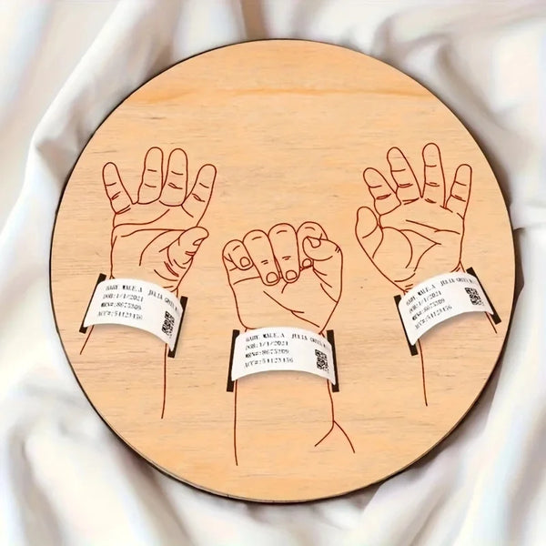 Señal de anuncio de bebé de madera con tres huellas de mano grabadas en un fondo circular de madera.