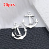 A pair of silver vintage ship anchor charms displayed on a black leather surface.
