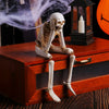 A set of three resin skeleton skull figurines displayed on a wooden box with an antique lantern.