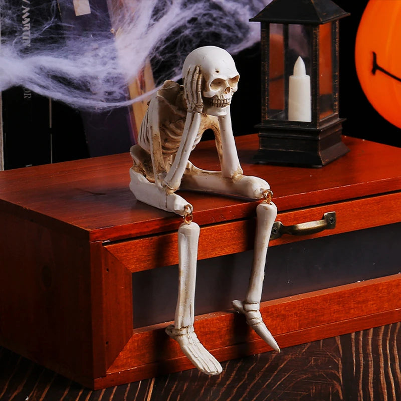 A set of three resin skeleton skull figurines displayed on a wooden box with an antique lantern.
