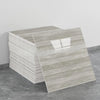 A stack of self-adhesive marble tile stickers in a light gray wood grain pattern on a gray floor.