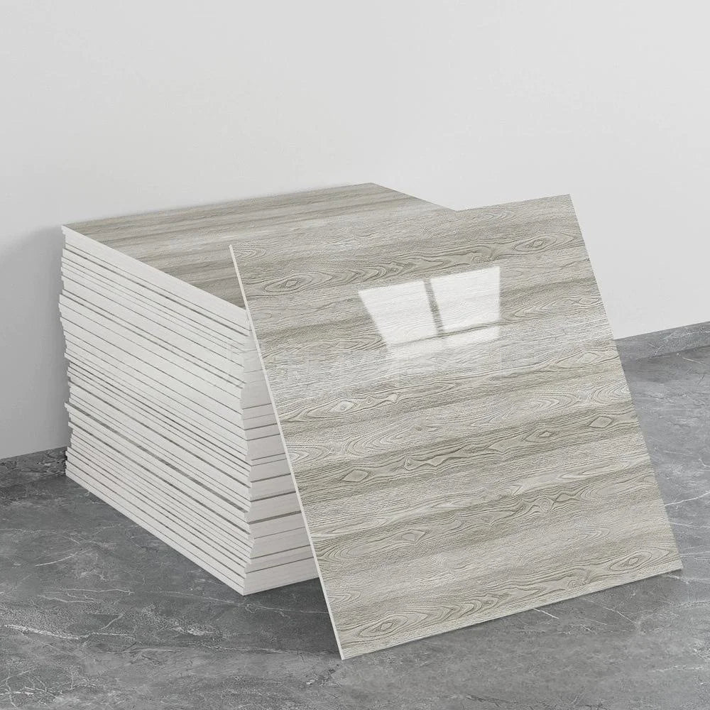 A stack of self-adhesive marble tile stickers in a light gray wood grain pattern on a gray floor.