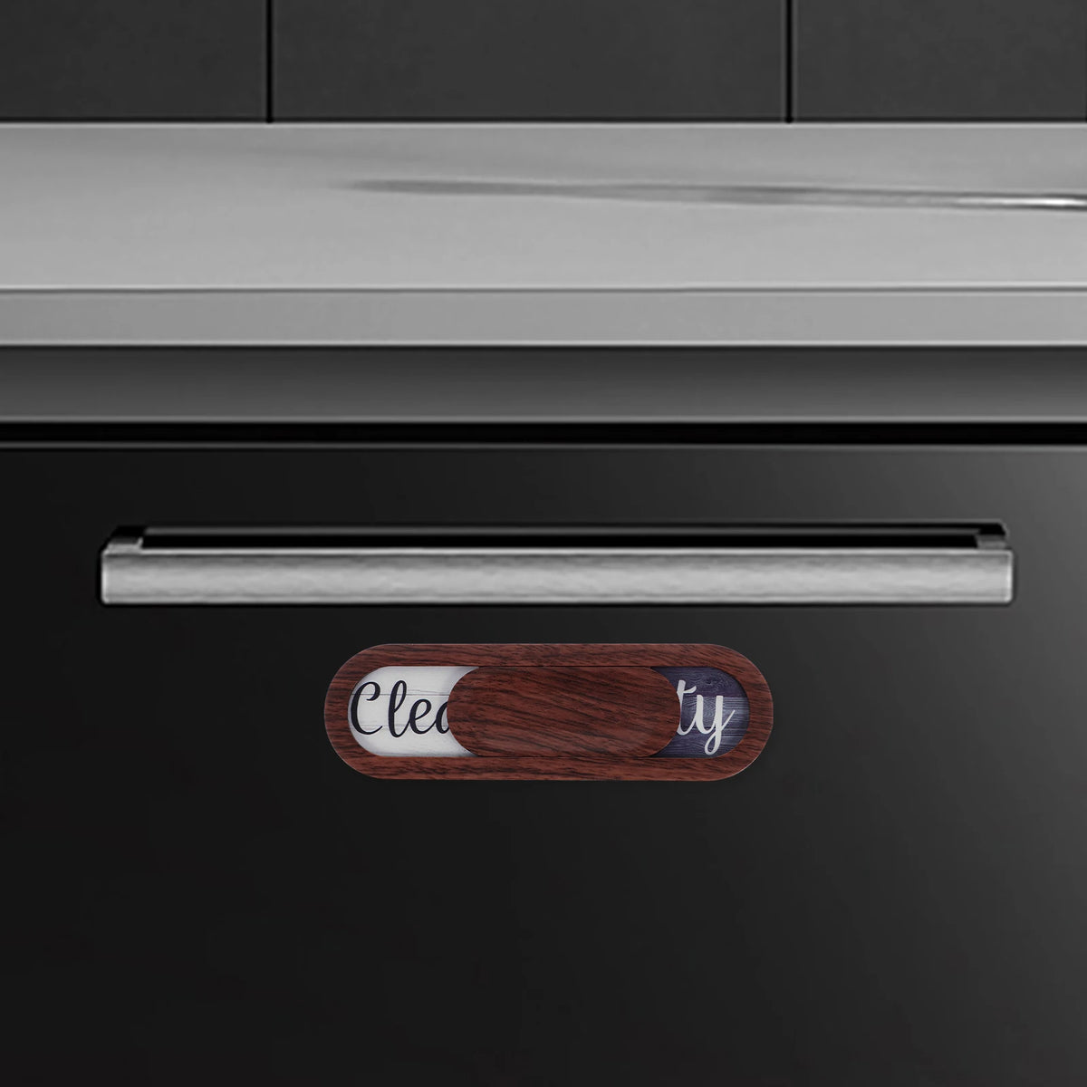 A close-up of a dishwasher panel showing a wooden indicator magnet labeled Clean and Dirty.