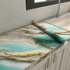 Marble pattern self-adhesive backsplash panel featuring turquoise and gold veining on a kitchen countertop.