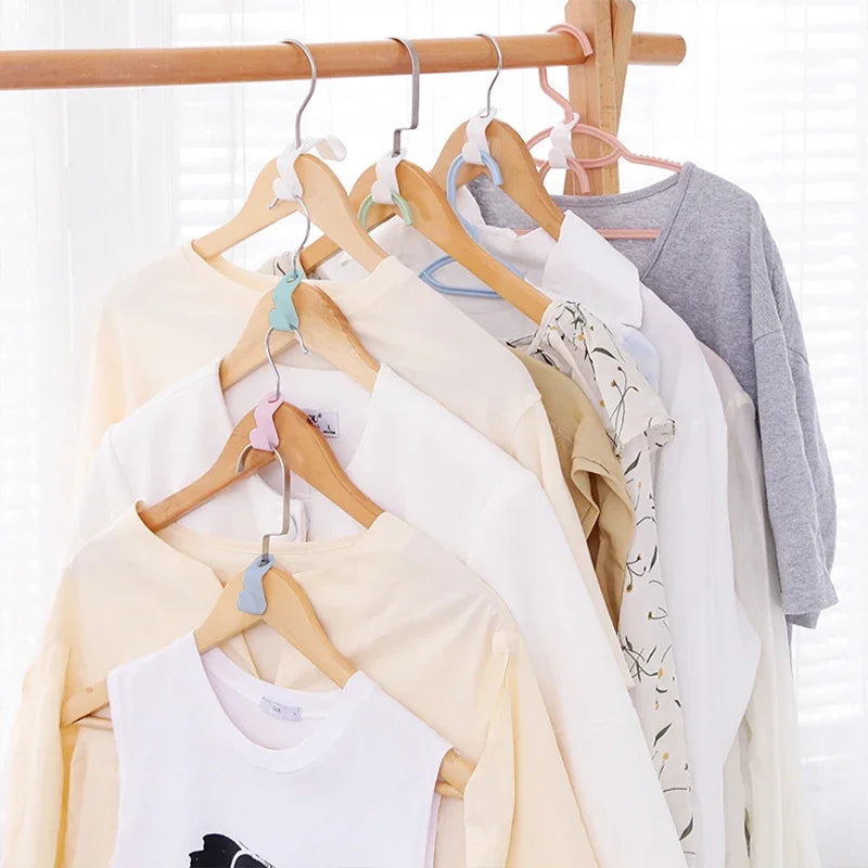 A collection of light-colored and gray t-shirts hanging on wooden hangers.