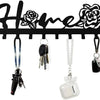 Black decorative metal wall-mounted key holder with seven hooks and various keys hanging from them