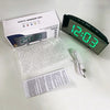 An LED mirror alarm clock with a large curved display and temperature sensor is shown next to its packaging and power cord.