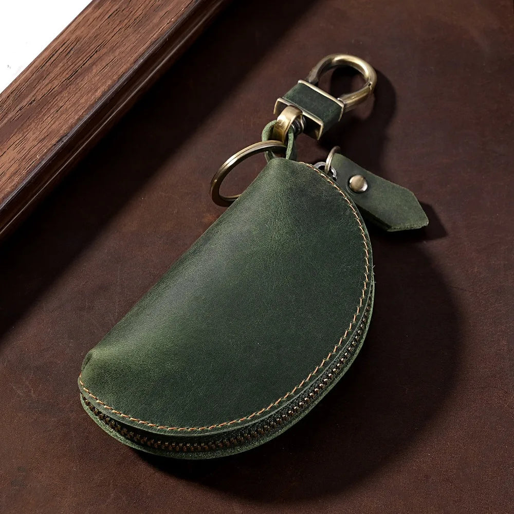 A dark olive green Crazy Horse leather key pouch with a brass carabiner attached.