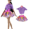 A handmade doll dress gown featuring purple and pink floral patterns with ruffled collars and bows.