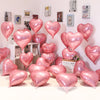 A collection of pink heart foil balloons displayed against a white wall.