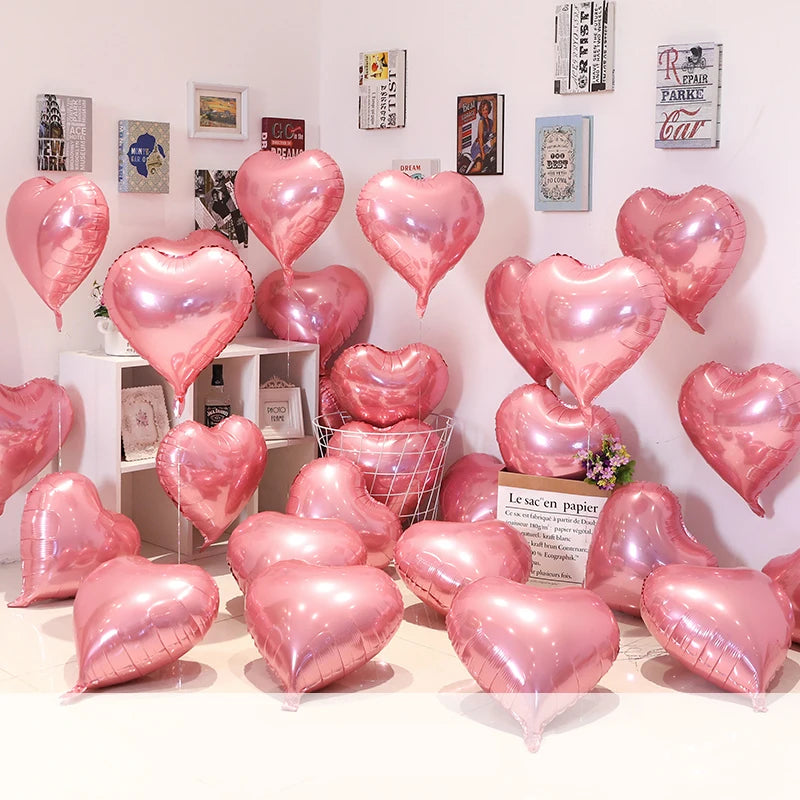 A collection of pink heart foil balloons displayed against a white wall.