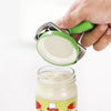 A hand is using a stainless steel multi-function bottle cap opener to remove the lid from a glass jar.