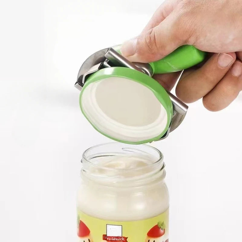 A hand is using a stainless steel multi-function bottle cap opener to remove the lid from a glass jar.
