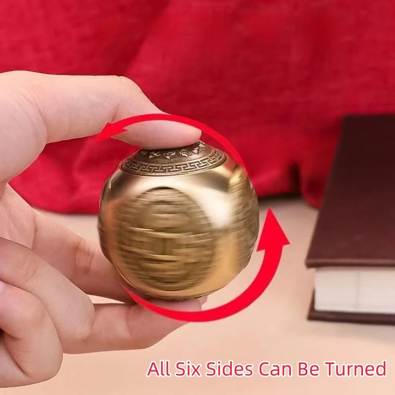 A hand holds a round, golden Chinese lucky coin spinner fidget toy against a red background.