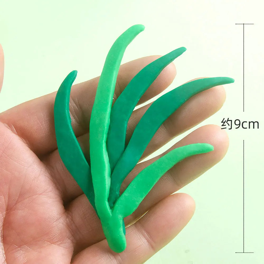 A hand holds a set of green ocean animal cake toppers including a crab, turtle, octopus, whale, starfish, and shell decor.