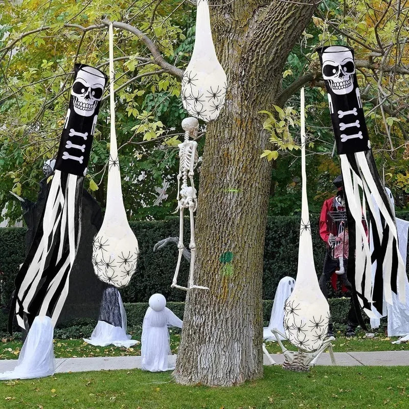 A display of Halloween decorations featuring skull-faced spider web silhouettes and light-up egg shapes hanging from tree bra