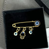 Elegant gold and silver evil eye brooch pin featuring a hand shape and an eye design.