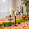 A set of minimalist Nordic round base candle holders with lit candles on a wooden table.