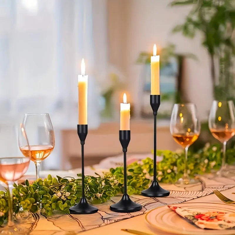 A set of minimalist Nordic round base candle holders with lit candles on a wooden table.