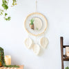 Boho macrame round wall mirror with fringe and feather accents hanging on a white wall