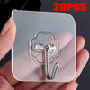 A hand holds a clear adhesive tile with multiple silver-colored wall hooks attached.