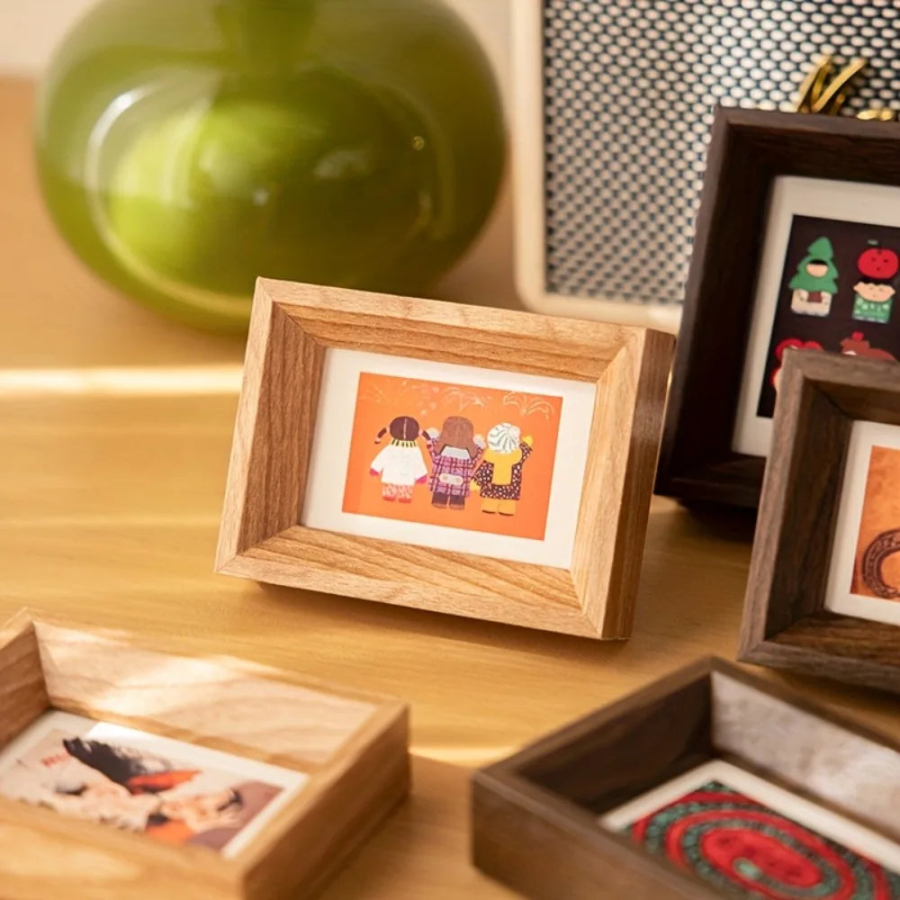 A wooden photo frame displaying a small colorful photograph on a light wood surface.