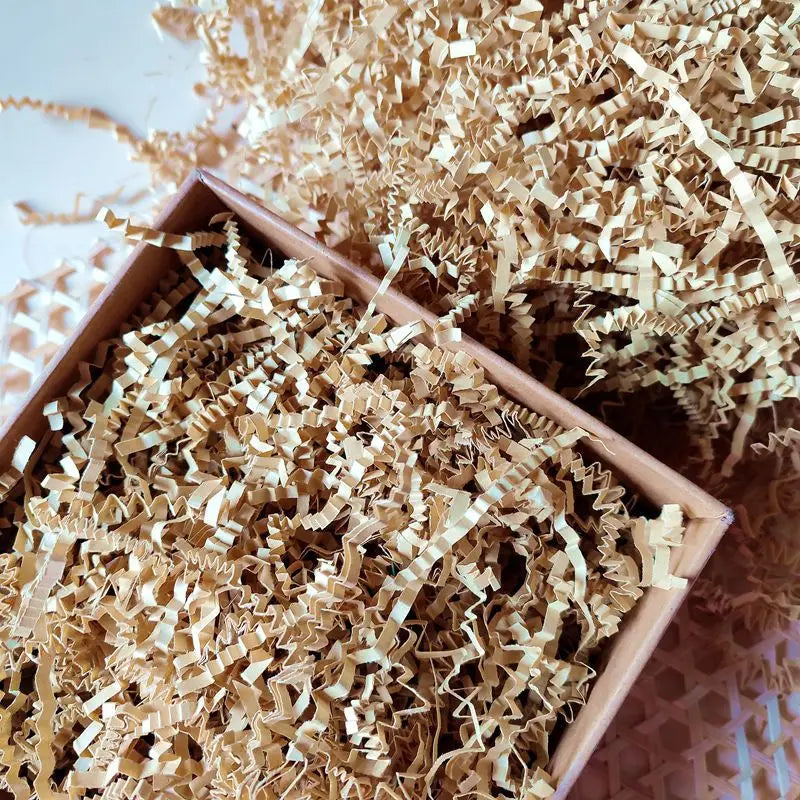 A pile of light brown crinkle cut paper shred filler material.