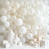 A wall decorated with numerous matte white latex balloons, including some wrapped in light gold boxes.