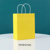 A bright yellow paper gift bag with white handles against a teal background.